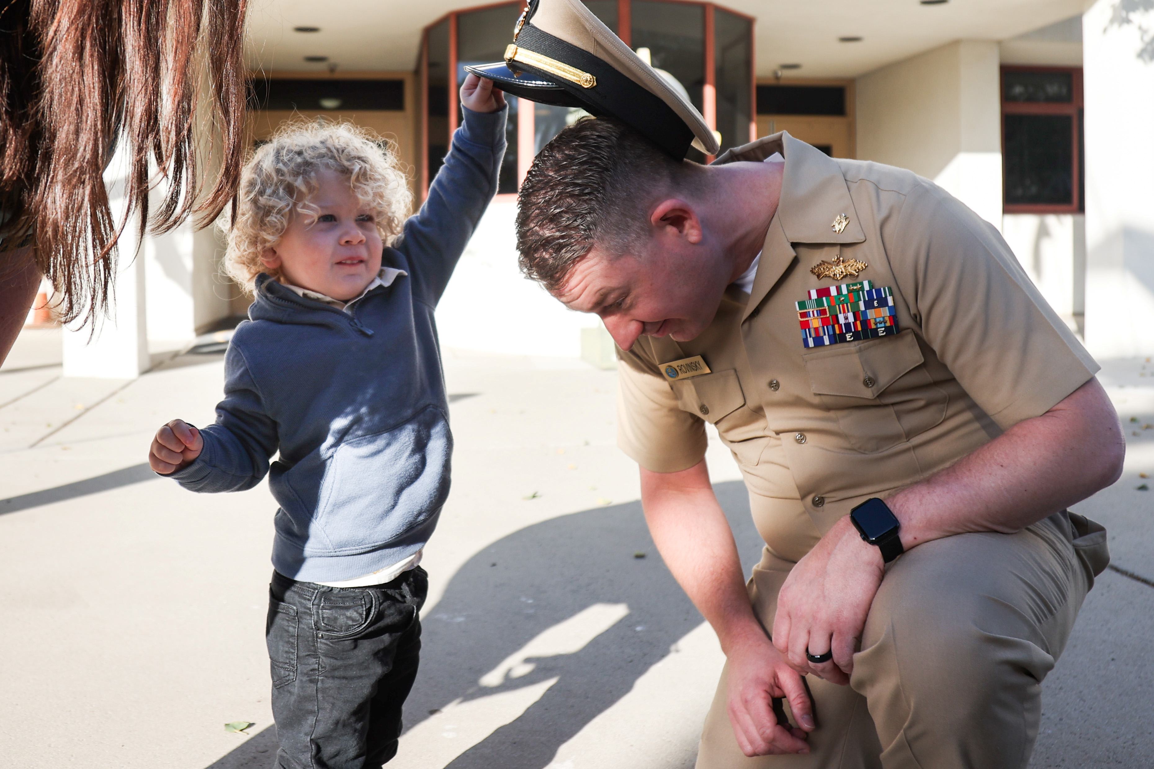 Child removing the military hat from man