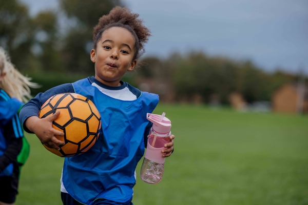 Girl on the field with soccer ball and water bottle