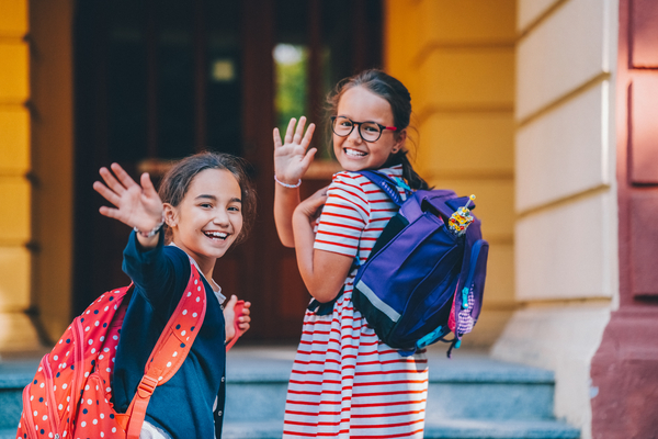 Two girls with backpacks at school