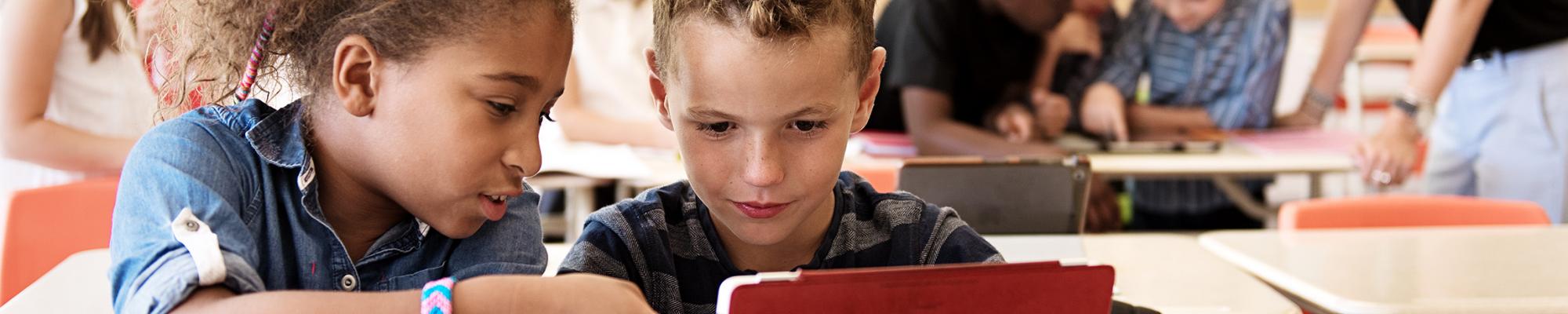 two students in class working on an ipad